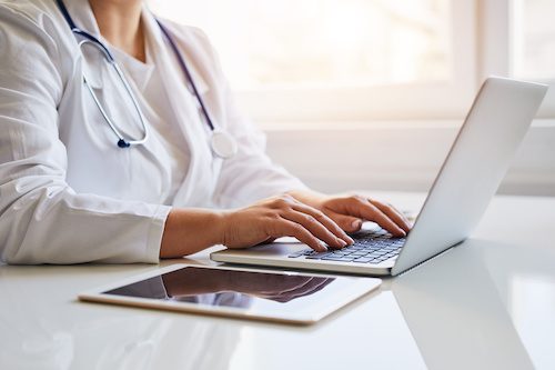 A doctor sitting at their desk, looking into healthcare revenue cycle optimization.