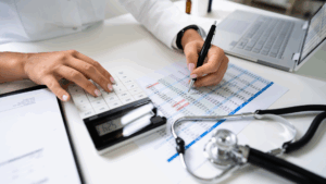 A doctor is writing on a paper with a stethoscope next to it