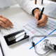 A doctor is writing on a paper with a stethoscope next to it