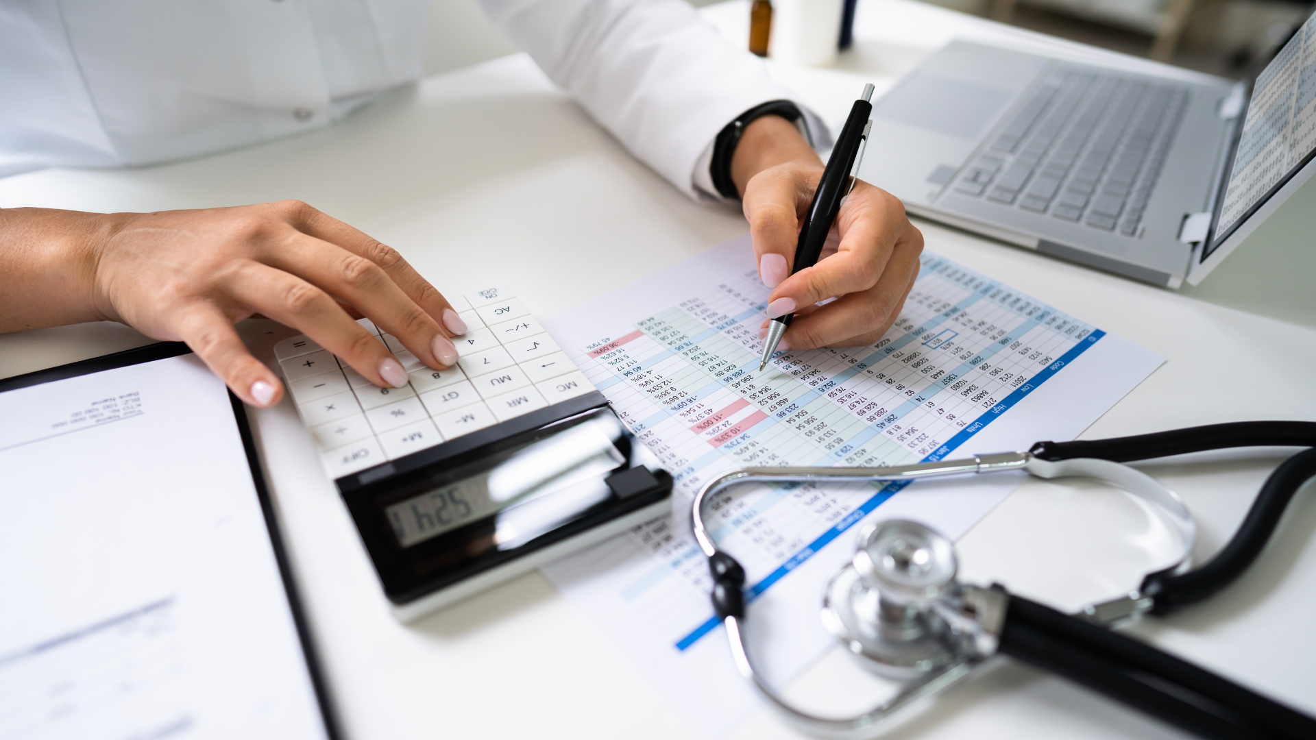 A doctor is writing on a paper with a stethoscope next to it
